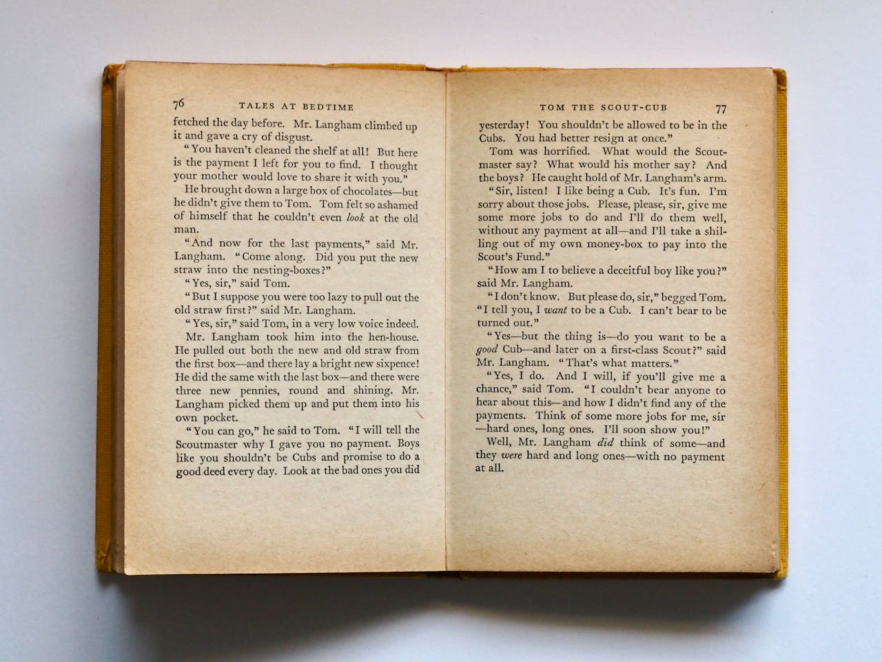 about-02 Vintage book opened to pages 76-77, displaying classic literature text in soft lighting.
